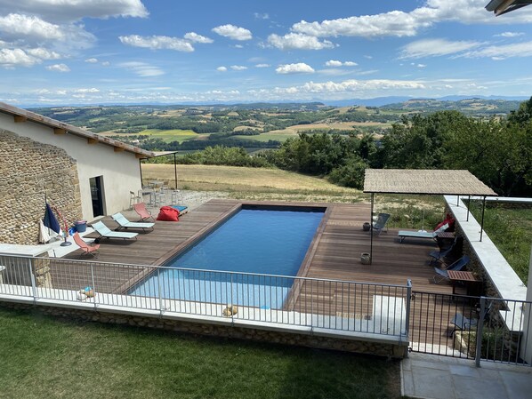 Piscina amb gandules i mur de pedra, amb vista a un paisatge idíl·lic.