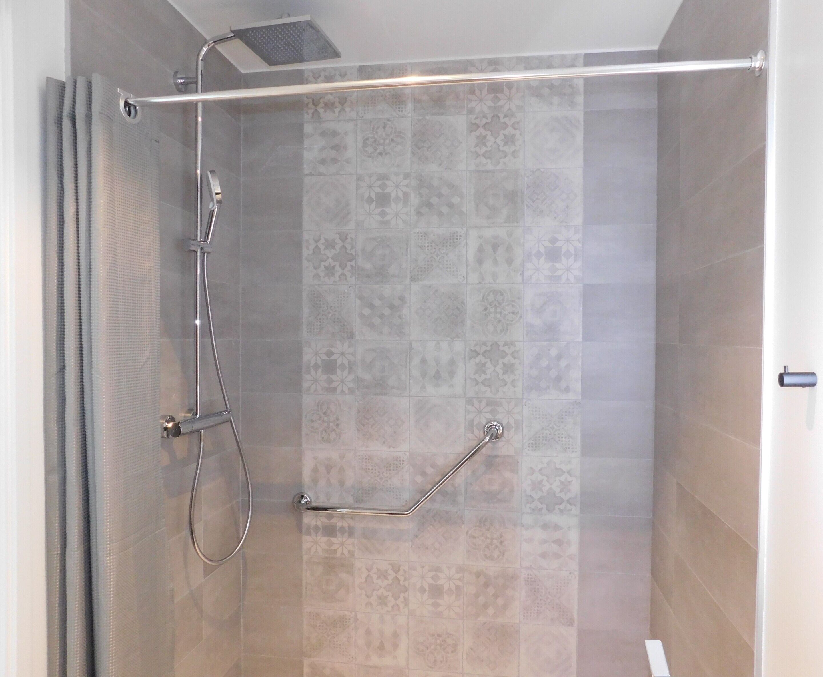 Ducha con puerta de vidrio, cabezal de ducha y barra de apoyo.