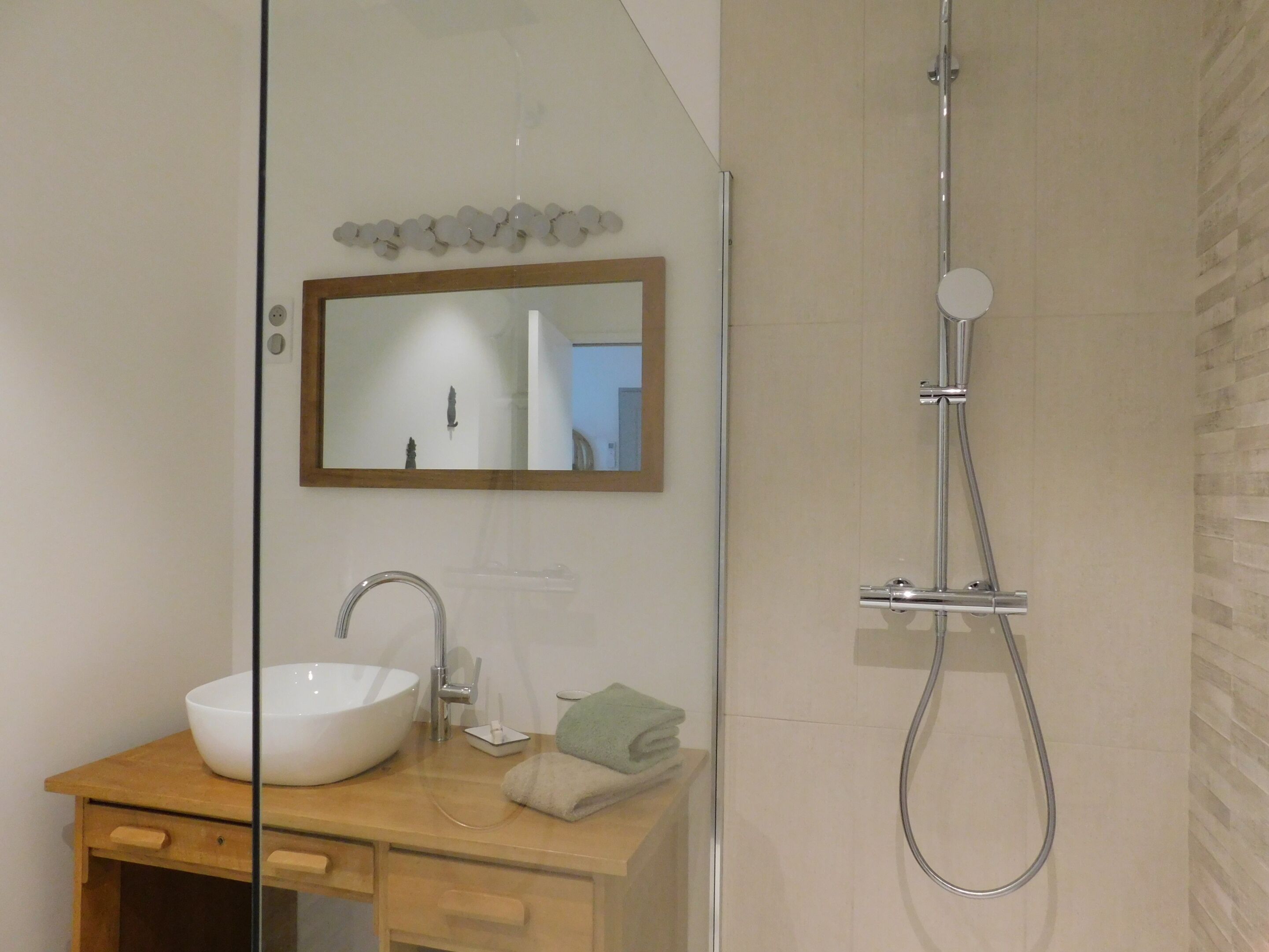 Une salle de bain moderne avec un grand lavabo blanc, un miroir et une douche.