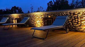 A wooden deck with two sun loungers and a stone wall. - La Maison de Paul & Margaux (Chateauneuf-de-Galaure)