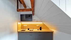 A modern kitchen with a wooden countertop, grey cabinets, and a built-in oven. - T House (Sibiu)