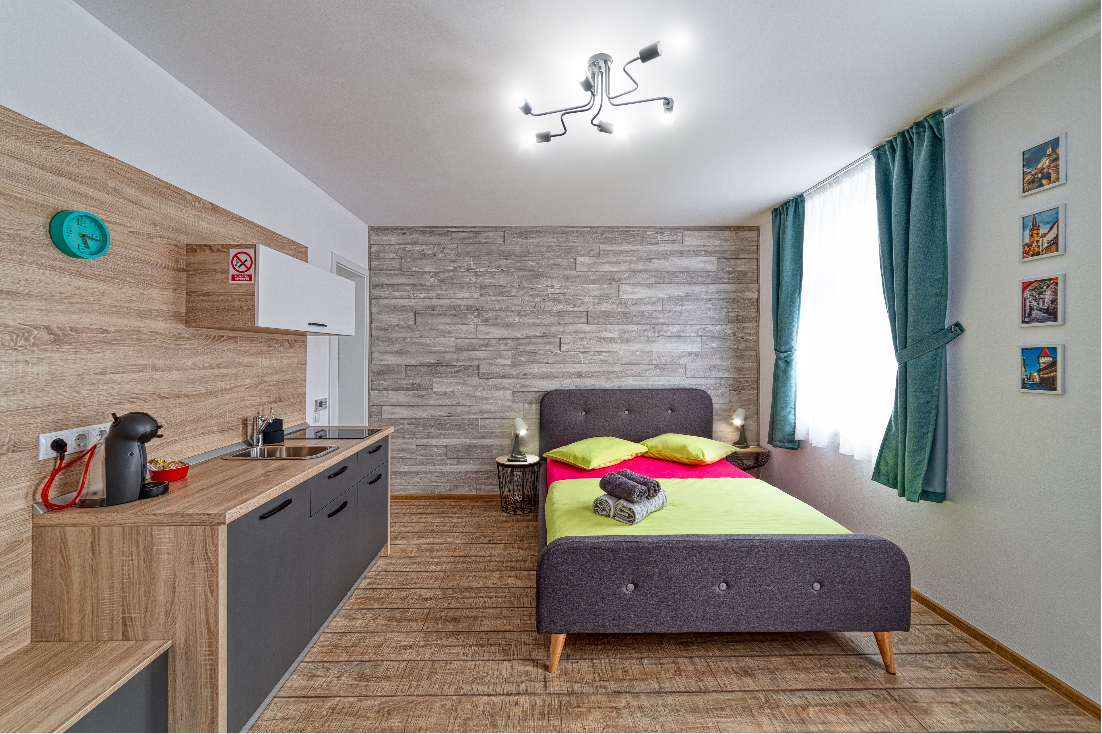 Una habitación moderna con cama, mesita de noche y una zona de cocina integrada.