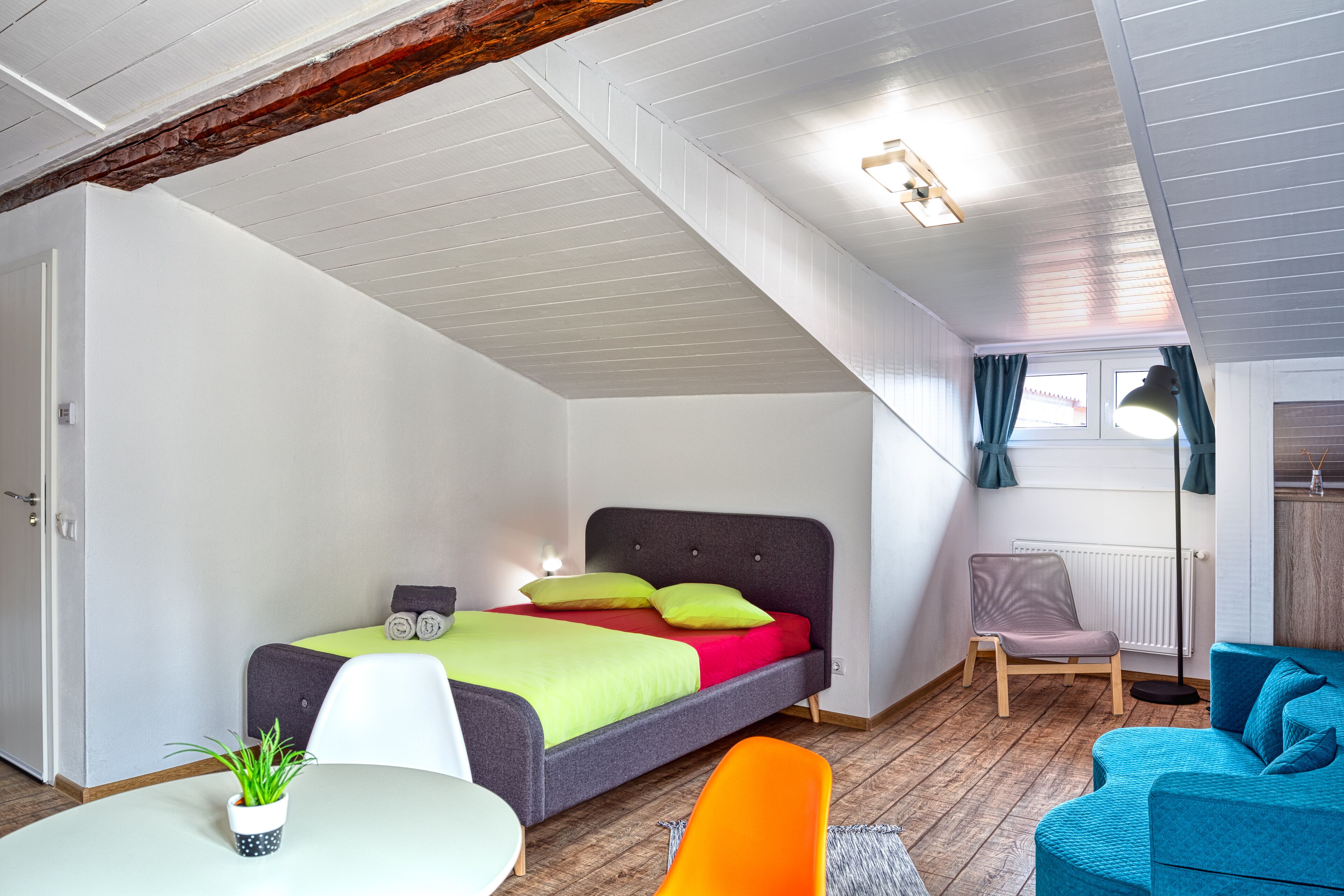 A modern bedroom with a bed, a chair, a sofa, and a small table.
