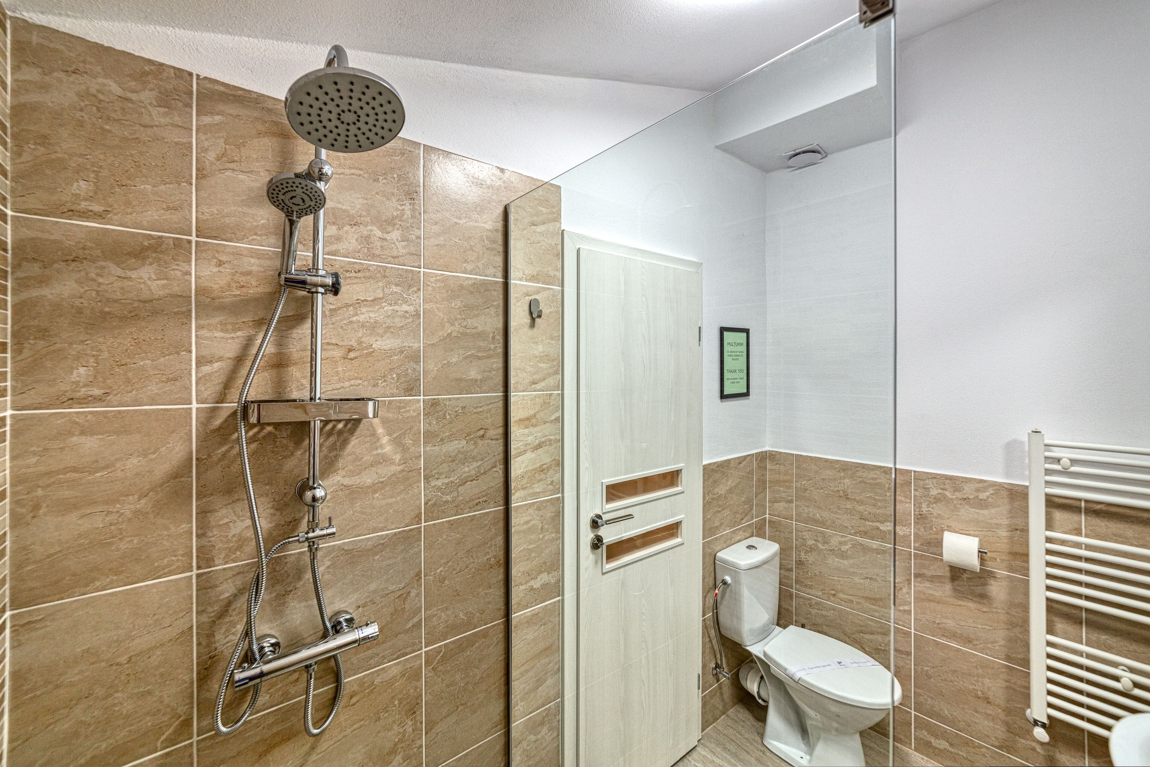 A bathroom with a shower, toilet, and a towel rack.