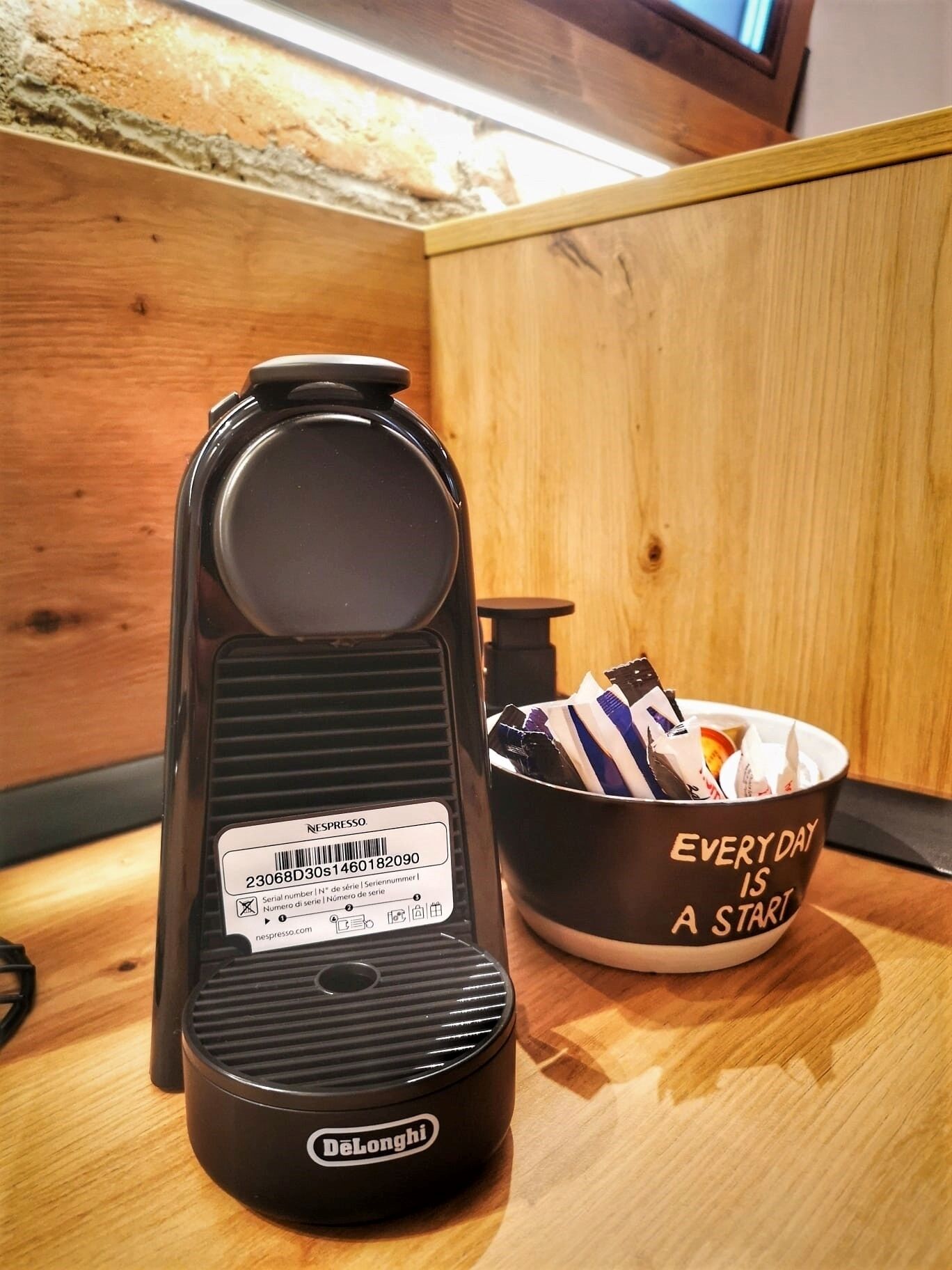A DeLonghi espresso machine with a label, next to a mug with motivational text.