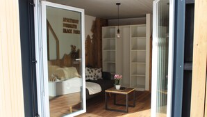Een moderne woonkamer met een bank, een salontafel en een glazen deur die naar een andere kamer leidt.