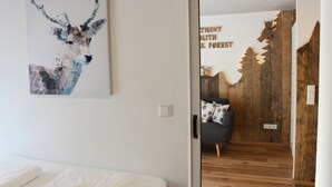 Een moderne hotelkamer met een geometrisch hertenkunstwerk, een houten accentmuur en een knus zitgedeelte met gestreepte kussens.