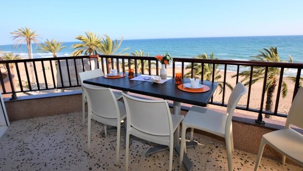 A balcony with a table and chairs overlooking a beach. - Leonor 3º2ª - Calafell (Calafell)