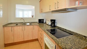 A kitchen with granite countertops, a built-in stove, a microwave, and a coffee maker. - Leonor 3º2ª - Calafell (Calafell)