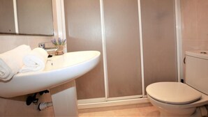 Un baño con lavamanos blanco, inodoro y cabina de ducha.