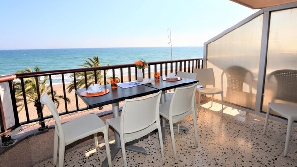 Un balcón con mesa y sillas, con vista al mar.