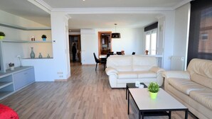 Una sala de estar moderna con un sofá, una mesa de centro y un área de comedor al fondo.