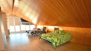Un amplio dormitorio en el ático con dos camas, suelo de madera y techo inclinado.