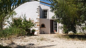 A building with a white exterior, a stone staircase, and a small arched window. - Romantic farm house with great garden (Peral)
