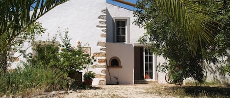 Un edificio con fachada blanca, una escalera de piedra y un pequeño ventanal de arco.