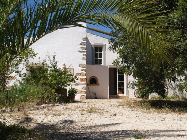 A building with a white exterior, a stone staircase, and a small arched window.