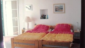 A bedroom with two wooden beds, a nightstand with a lamp, and a small shelf with books. - Romantic farm house with great garden (Peral)