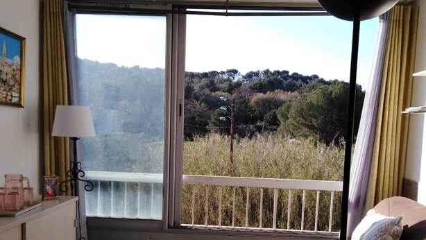 Une chambre avec un balcon, un canapé, une table et une lampe.