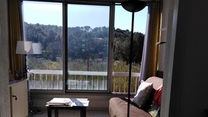 Un balcon avec un canapé, une table et une vue sur une zone boisée.