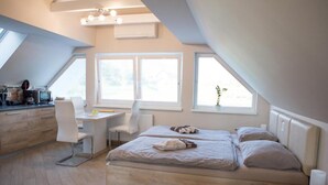 Ein modernes Schlafzimmer mit einem Schreibtisch im Loft-Stil, einem Bett mit zwei Kissen und Blick ins Freie.