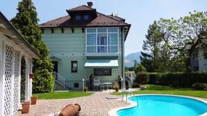 Ein Haus mit Swimmingpool, überdachter Terrasse und Bergblick.