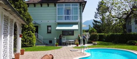 A house with a swimming pool, a covered patio, and a view of mountains.