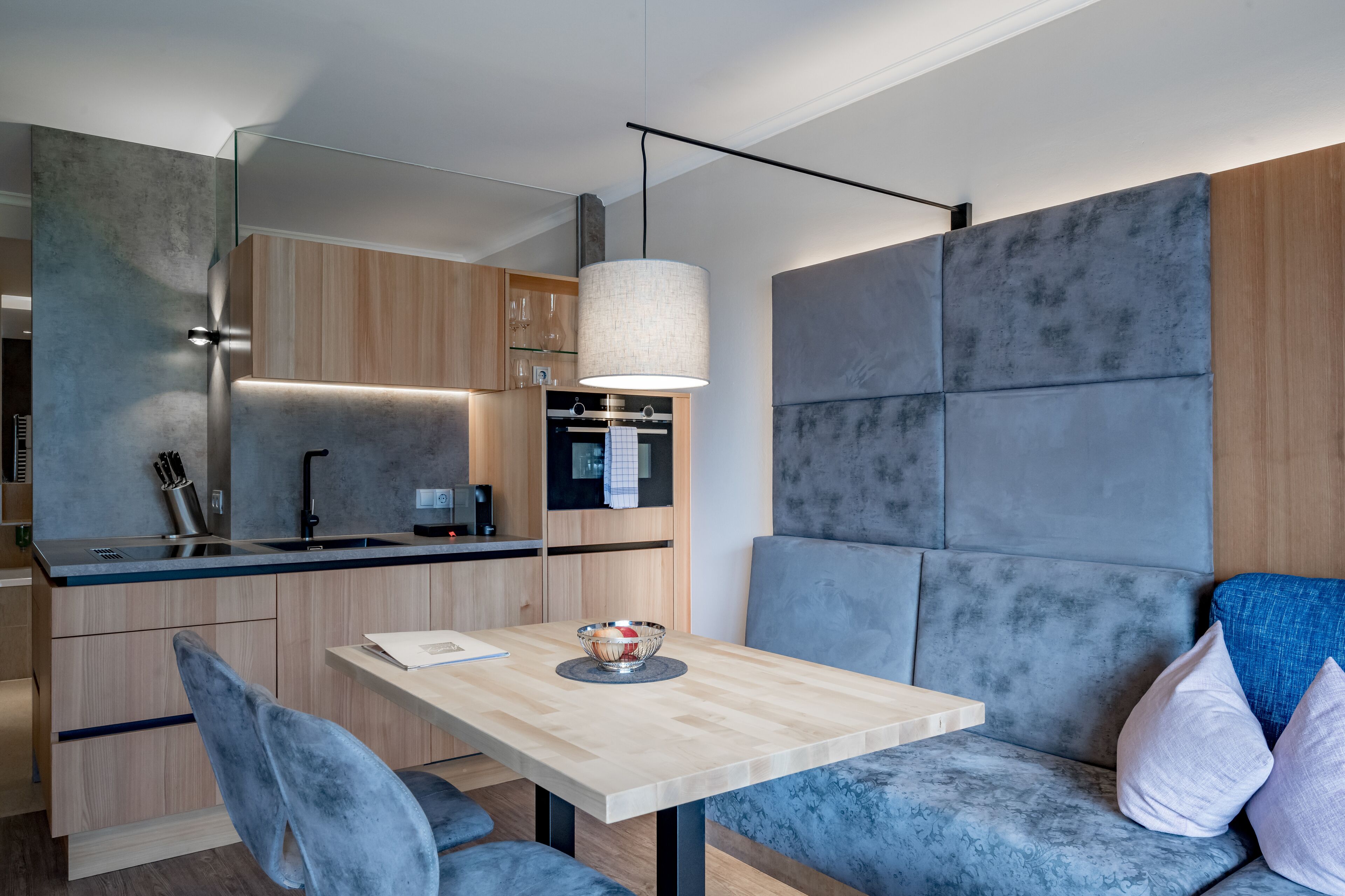A modern kitchen with a wooden countertop, a built-in oven, and a hanging light fixture.