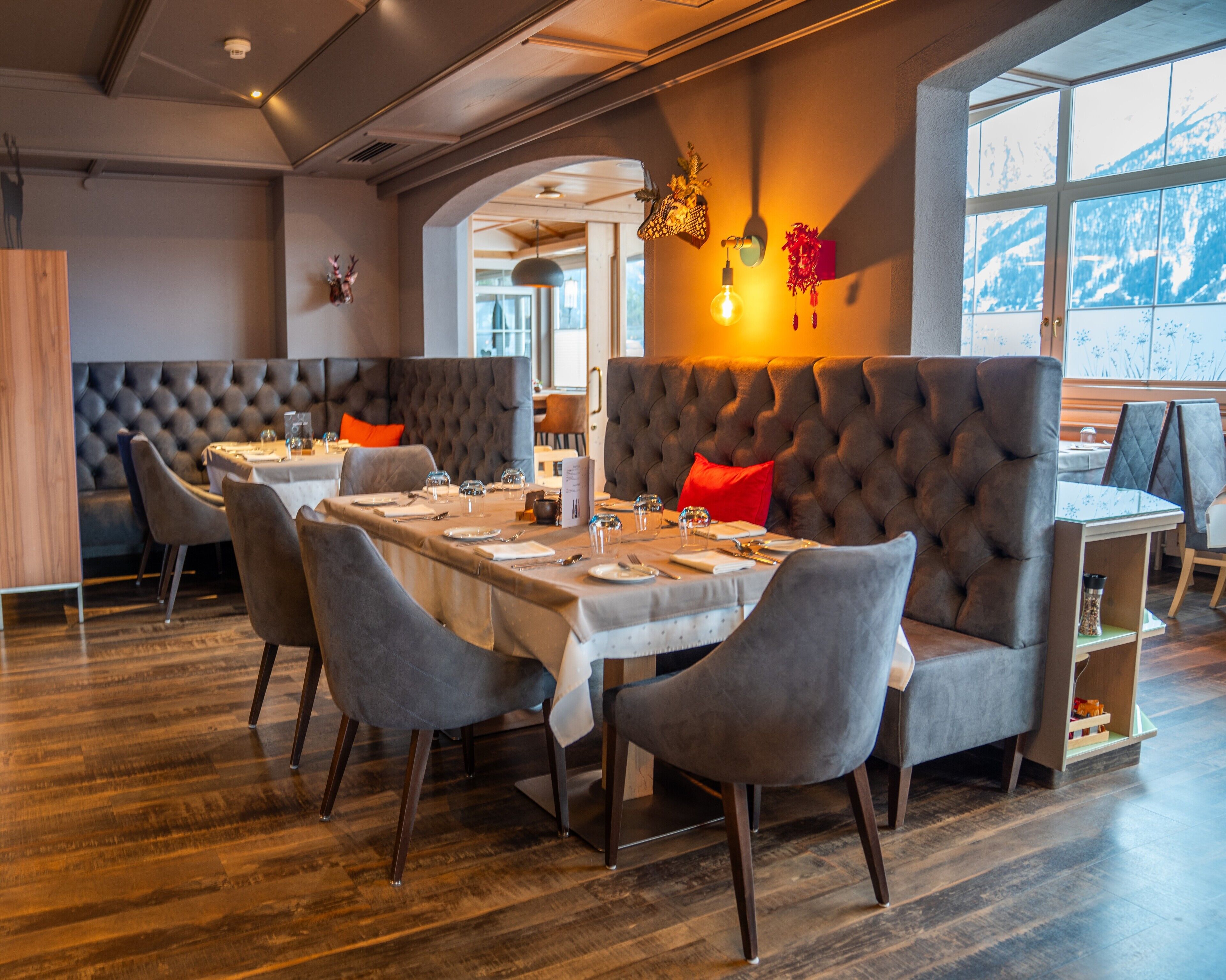 Un restaurante con techo alto, suelo de madera y un rincón de estar acogedor con sillas acolchadas y un sofá.