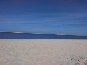 Une plage avec un ciel dégagé et un rivage sablonneux.