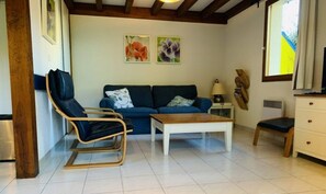 A living room with a sofa, a chair, a coffee table, and a small cabinet. - In Residence with swimming pool, Tennis, children's games 8 minutes from contis beach (Saint-Julien-en-Born)