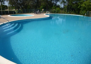A clear blue swimming pool with a paved deck area and lounge chairs. - In Residence with swimming pool, Tennis, children's games 8 minutes from contis beach (Saint-Julien-en-Born)