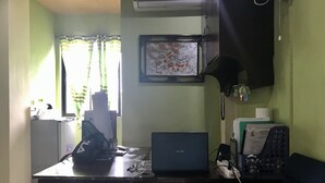 A room with a desk, a laptop, a telephone, and an air conditioning unit. - Rjat Guesthouse (Calamba)