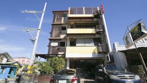 A multi-story building with balconies and a garage entrance. - Rjat Guesthouse (Calamba)
