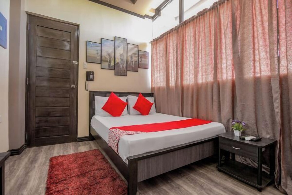 Une chambre à coucher avec un lit, une table de chevet, un tapis rouge, une porte et un téléphone fixé au mur.