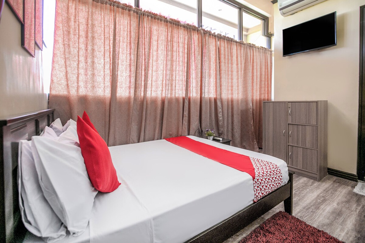 Una habitación de hotel con cama, televisión, aire acondicionado y armario.