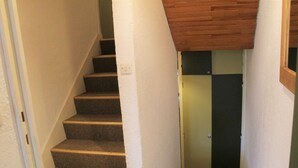 Una escalera con peldaños alfombrados que conduce a una puerta con un interior oscuro.
