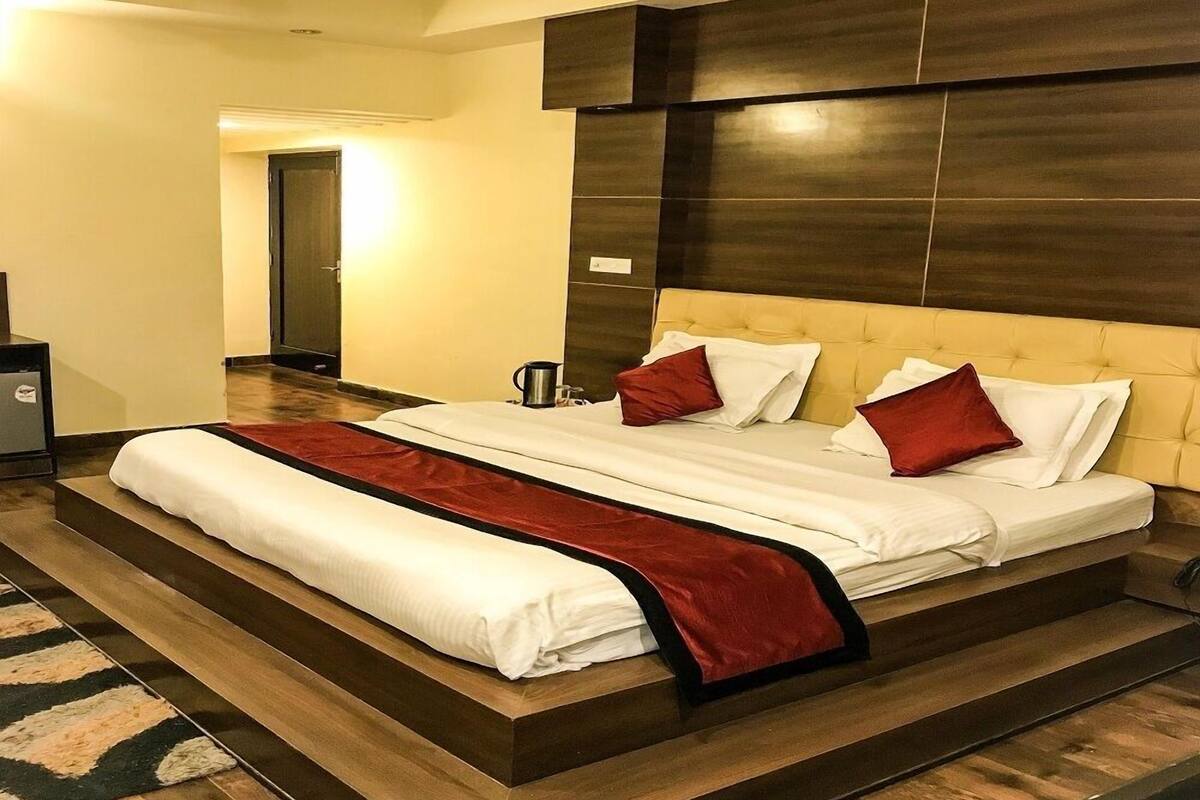 Habitación de hotel moderna con una cama grande, cabecera de madera y un corredor decorativo rojo.