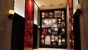 A hallway with a checkered floor, red walls, and a display of various items including a clock, framed pictures, and decorative objects. - DEL style Osaka Shin Umeda by Daiwa Roynet Hotel (Osaka)