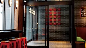 A modern interior with a glass partition, red seating, and a brick wall with a light fixture. - DEL style Osaka Shin Umeda by Daiwa Roynet Hotel (Osaka)