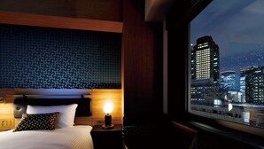 A hotel room with a bed, a nightstand with a lamp, a window with a city view, and a patterned wall. - DEL style Osaka Shin Umeda by Daiwa Roynet Hotel (Osaka)