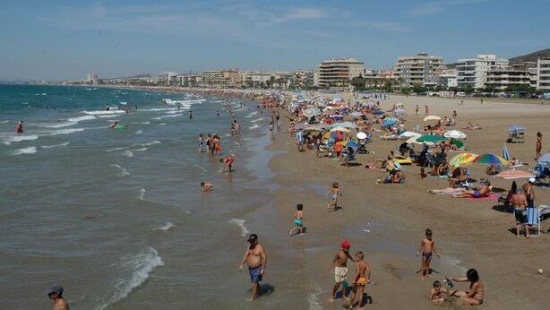Une plage bondée où les gens se prélassent au soleil et se baignent.