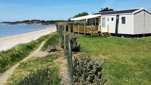 A mobile home with a deck overlooking a beach.