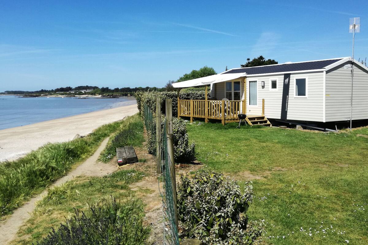 Une maison mobile dotée d’une terrasse donnant sur une plage.