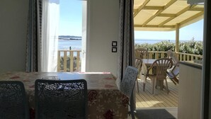 A balcony with a table and chairs, a view of the sea, and a covered area with a table and chairs.