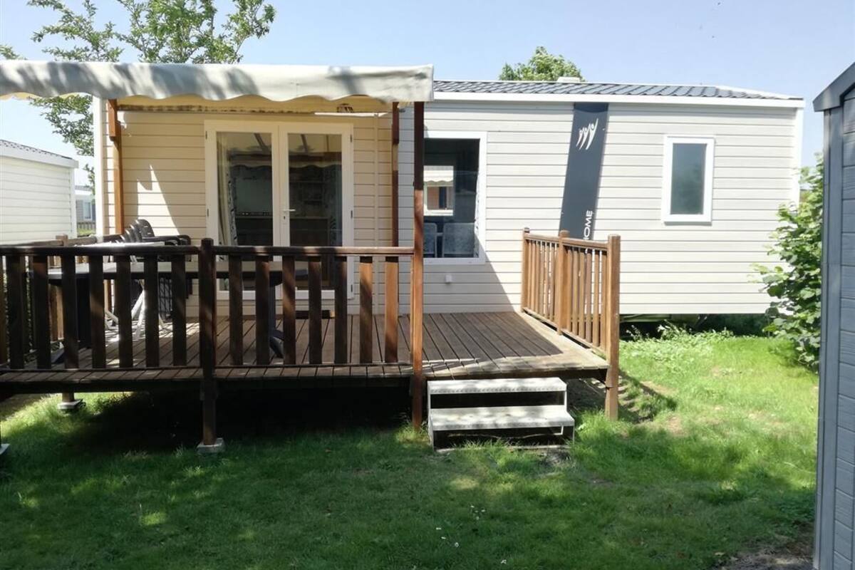 Une maison mobile dotée d’une véranda, d’une petite terrasse et d’une porte d’entrée.
