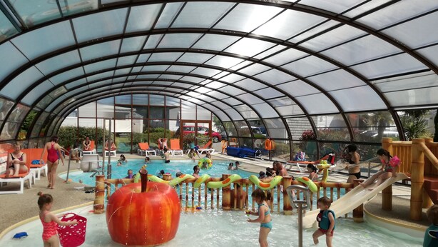 An indoor water park with a covered swimming pool, slides, and various water play areas.