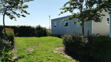 A mobile home with a small front yard, a pathway, and a hedge.