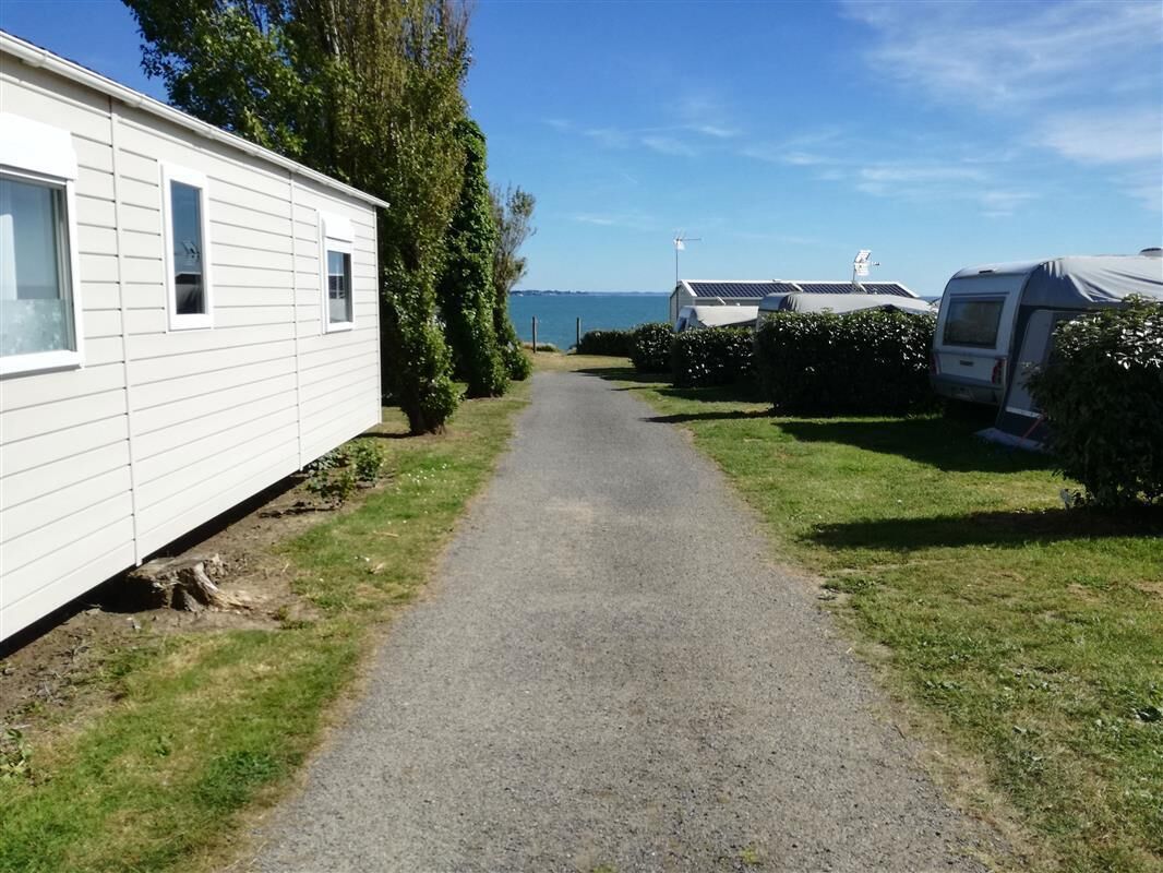 A gravel path leading to mobile homes with a view of the sea.