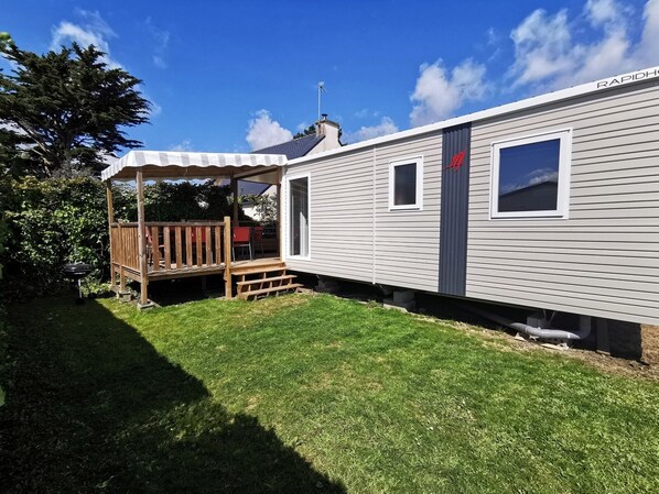 A mobile home with a covered patio, a small deck, and a satellite dish.