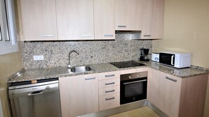 A compact kitchen with a dishwasher, a microwave, a coffee maker, and a built-in oven. - Apartament Suiza - Calafell (Calafell)